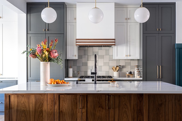 A bright kitchen featuring a pristine white countertop, complemented by a charming flower vase. Three elegant hanging lamps illuminate the space, casting a warm glow