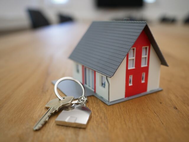 key and pendant beside small model of a house